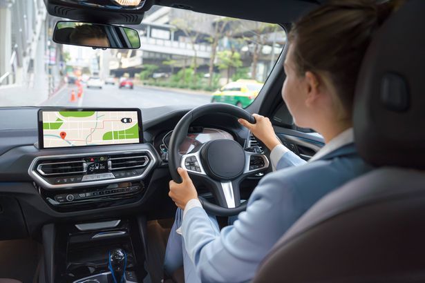 imported-1_Back-view-of-young-female-driver-sitting-at-steering-wheel-and-looking-GPS-navigation-screen-during-road-trip.jpg