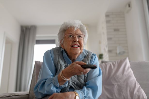 imported-0_Low-angle-view-of-adorable-old-woman-watching-television-holding-TV-remote-controller.jpg