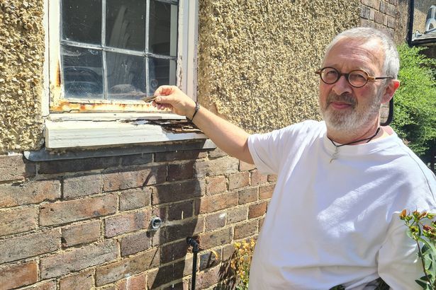 imported-1_Andrew-Brown-holding-a-piece-of-the-rotting-window-frame.jpg